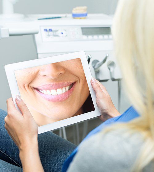 Woman looking at virtual smile design image on tablet computer