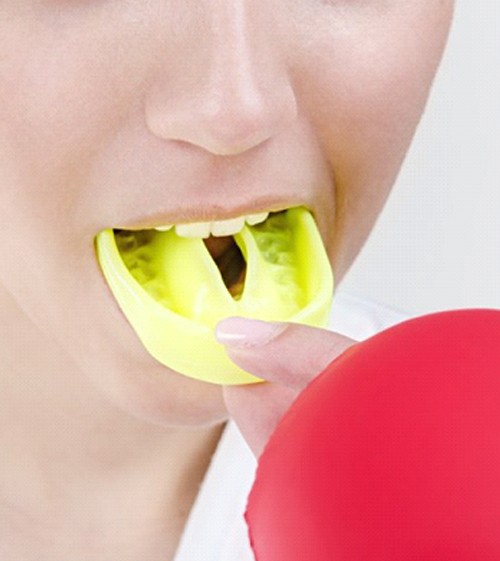 person putting on a yellow mouthguard