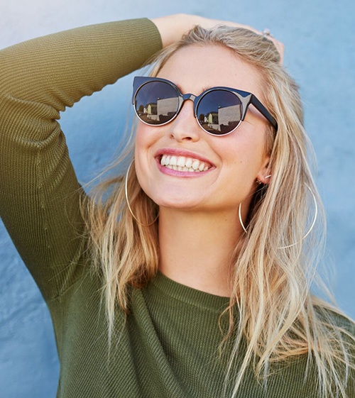 young woman wearing sunglasses and smiling with veneers in North Grafton 
