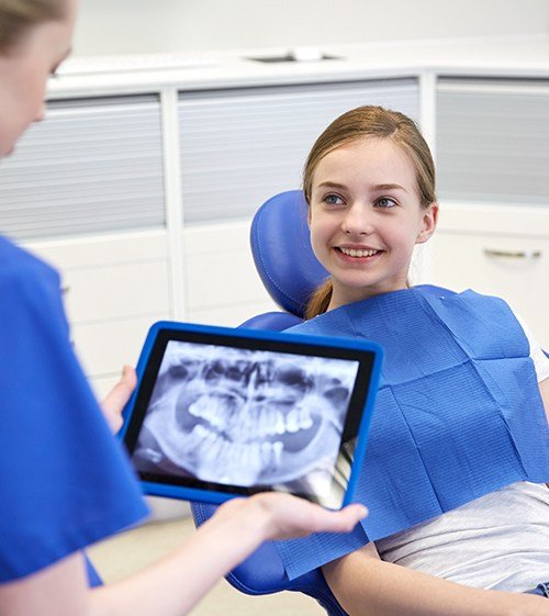 Child smiling at dentist looking at dental x-rays
