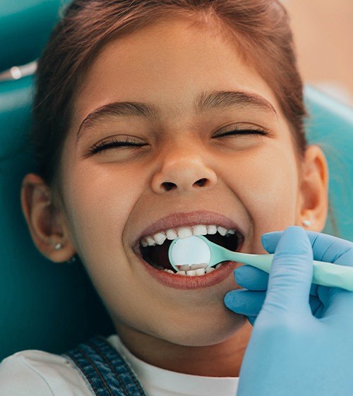 Dentist checking child's smile after dental sealant placement