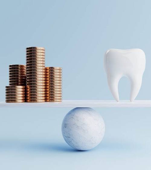 A stack of gold coins and a large model tooth placed on a balance beam