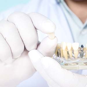 Dentist holding dental crown for dental implant in North Grafton