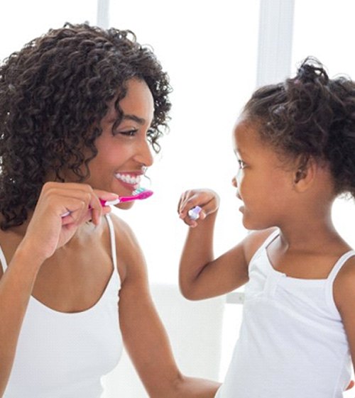 mother and daughter brushing their teeth together