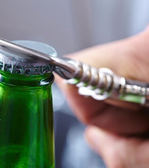 person opening a glass bottle with a bottle opener