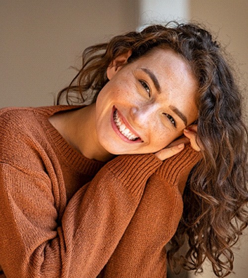 Woman in orange sweater sitting and smiling