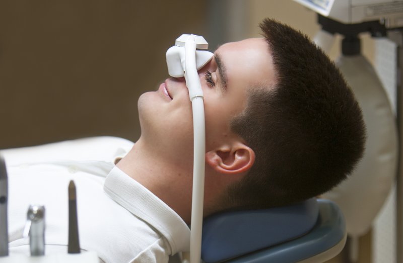 a young man wearing a nasal mask and receiving nitrous oxide during an appointment